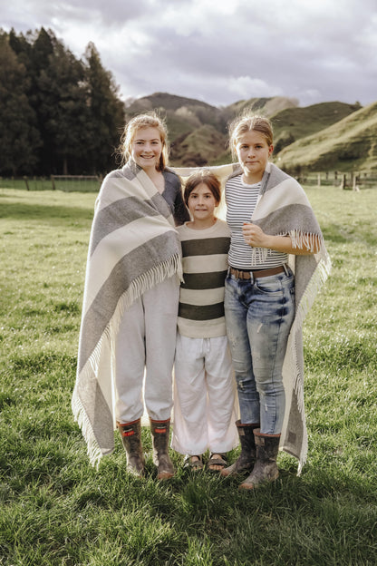 Three people standing in a grassy field with mountains in the background