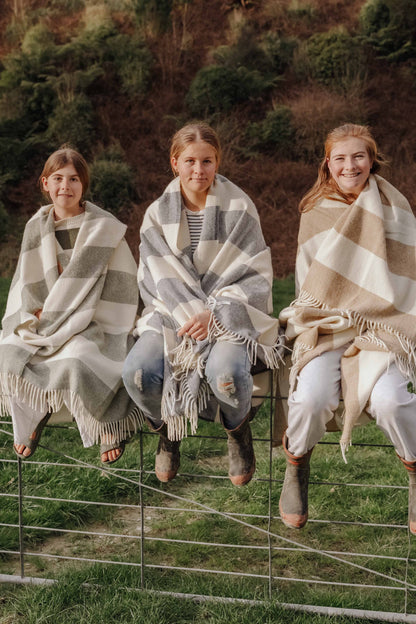 3 girls sitting on fence wrapped in blankets