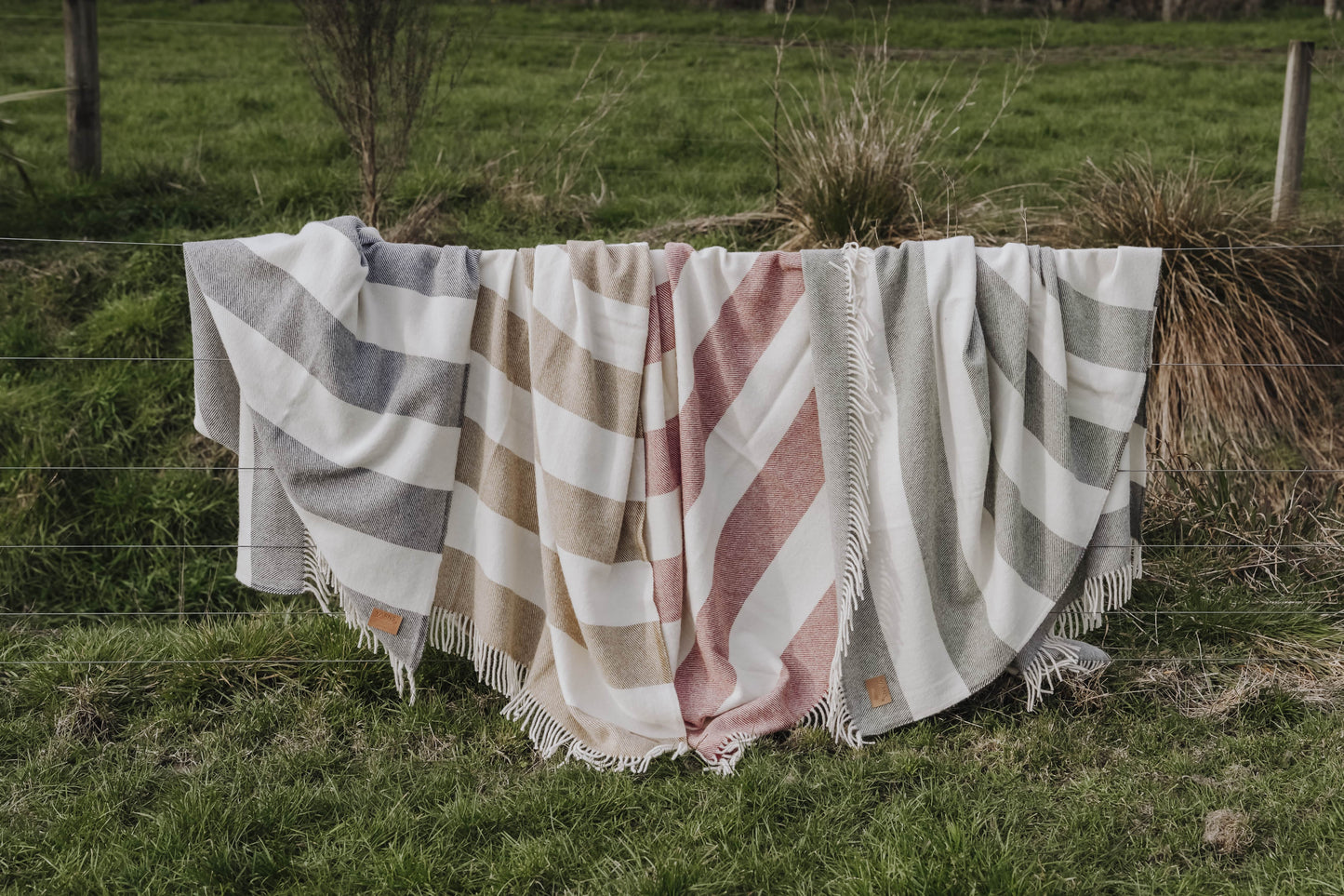 Checkered blanket draped over a fence in a grassy field