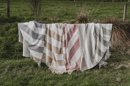 Checkered blanket draped over a fence in a grassy field